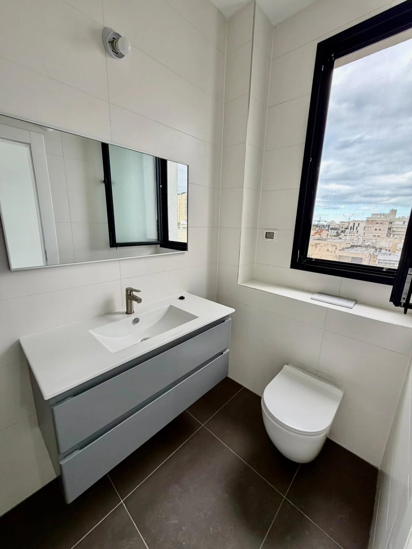 Salle d'eau moderne avec lavabo et fenêtre vue ville