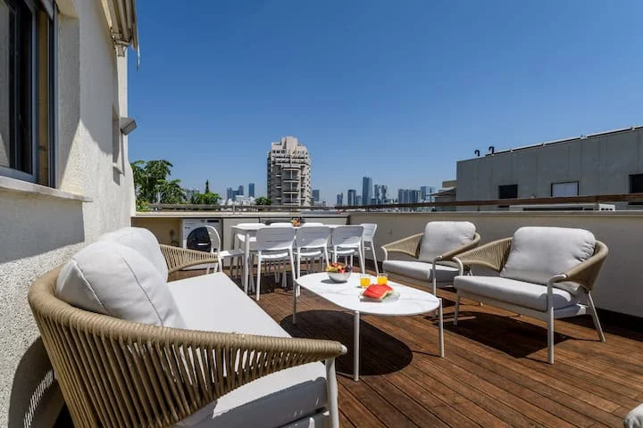 Terrasse rooftop avec salon de jardin et vue sur la skyline de Tel Aviv