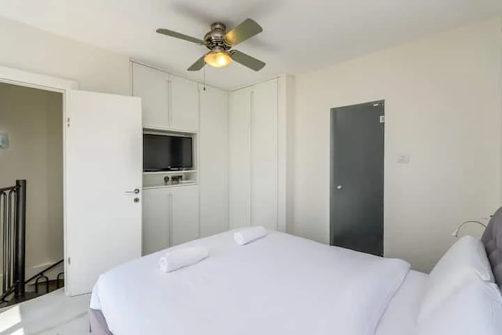 Chambre avec armoires blanches et télévision encastrée
