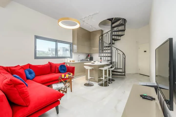 Salon avec canapé rouge et escalier en colimaçon