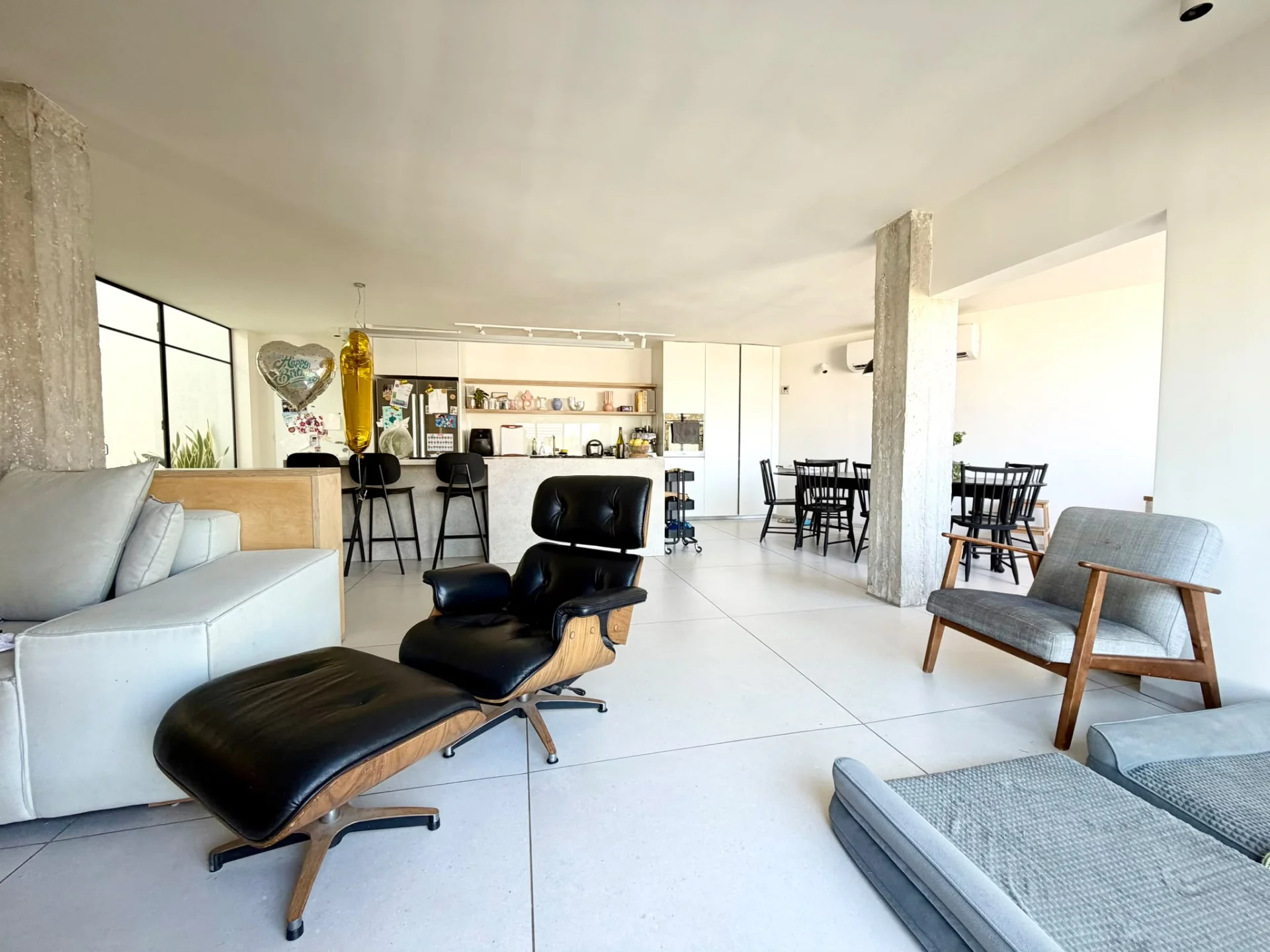 Séjour ouvert avec fauteuil Eames, canapé et cuisine en arrière-plan
