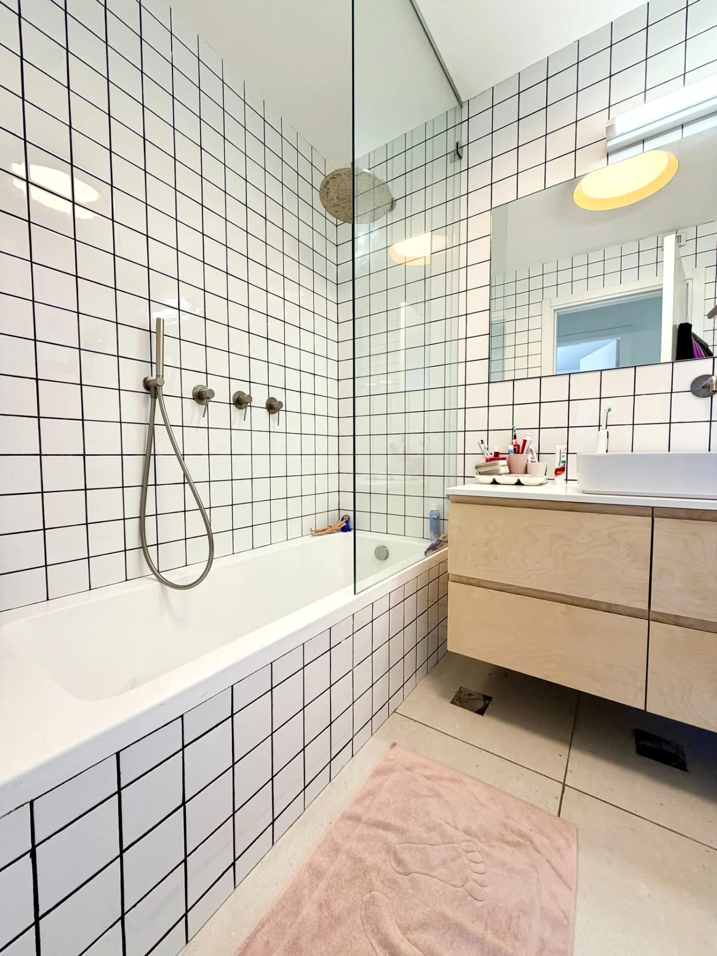 Salle de bain avec baignoire, carrelage blanc quadrillé et meuble vasque