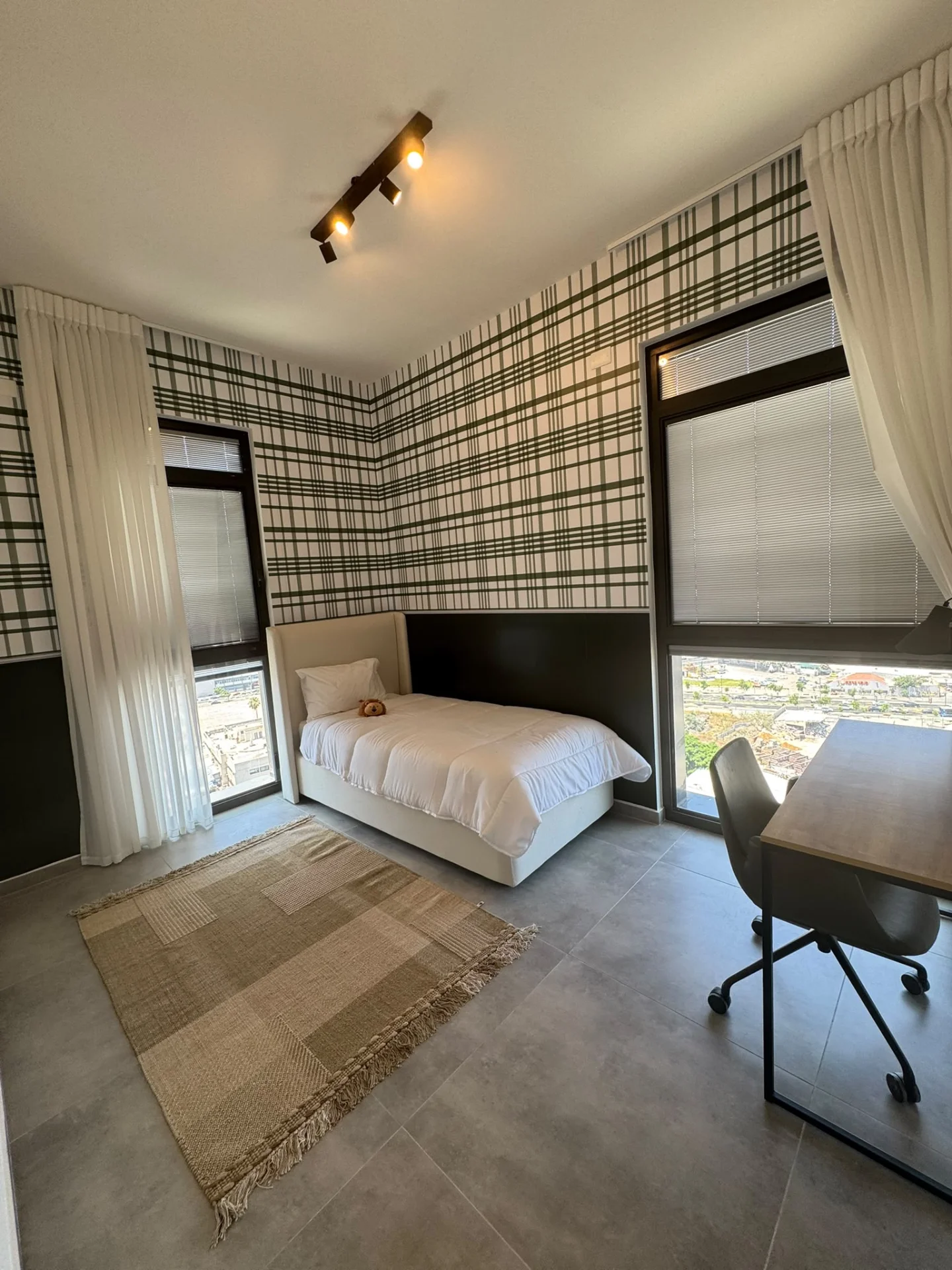 Chambre enfant avec papier peint à carreaux et vue ville
