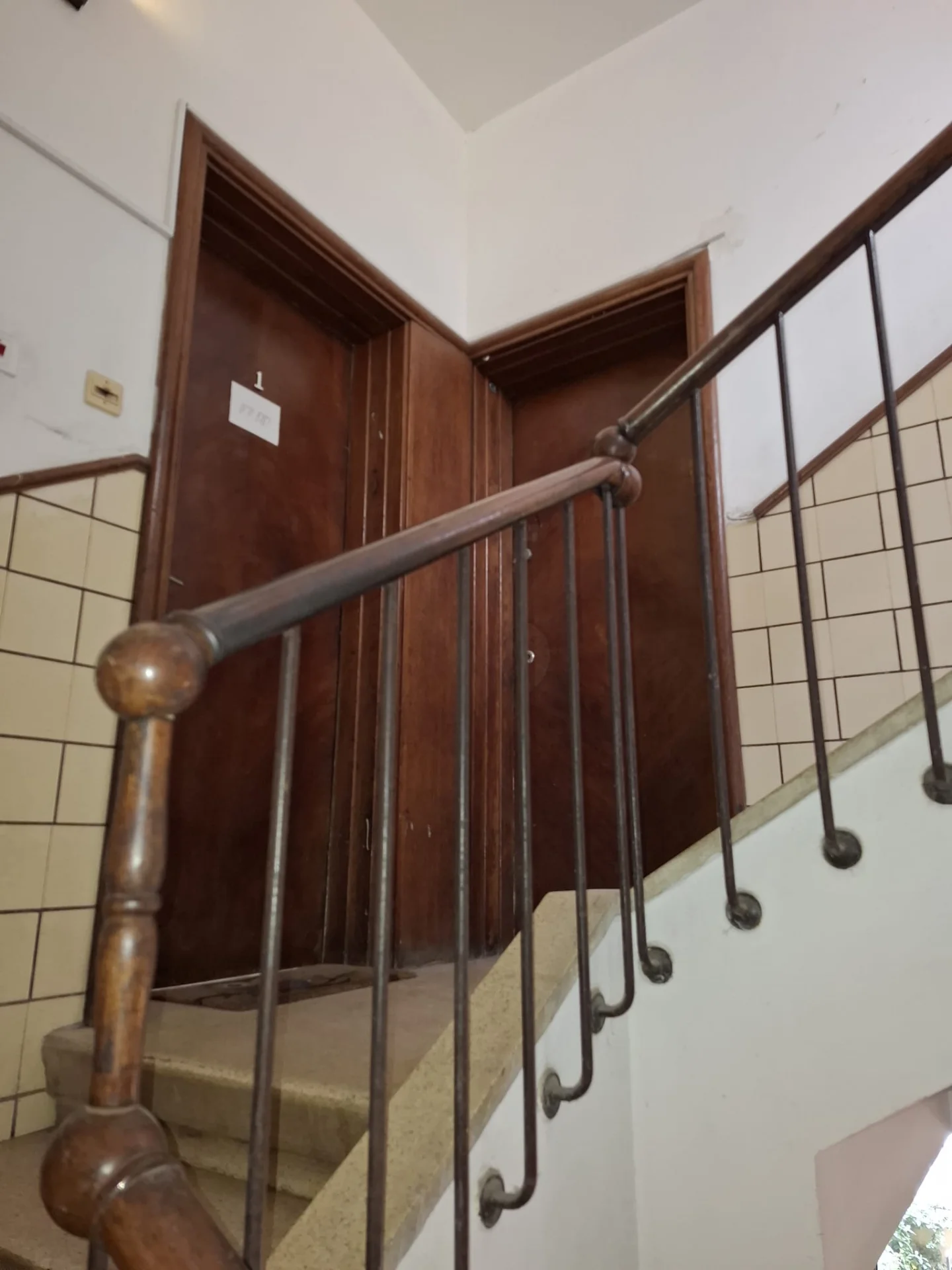 Cage d'escalier avec rampe en bois et porte d'entrée