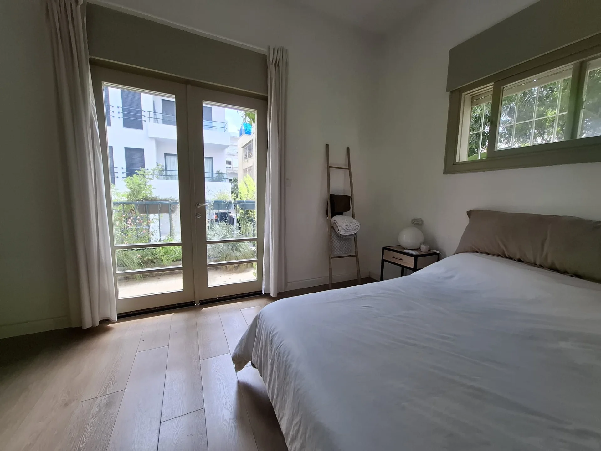 Chambre vue depuis le lit avec portes-fenêtres sur balcon