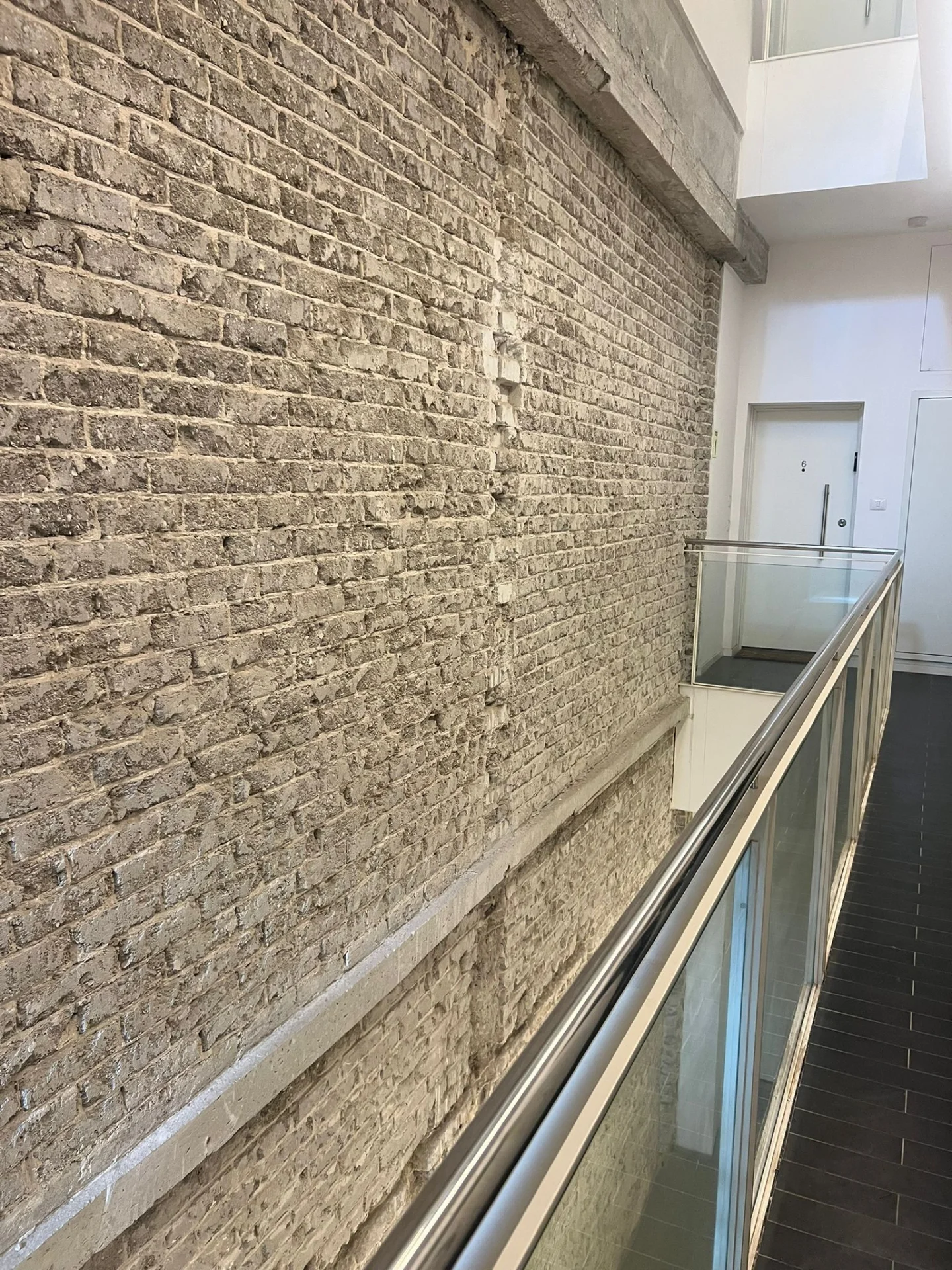 Cage d'escalier avec mur en pierres apparentes et rambarde en verre