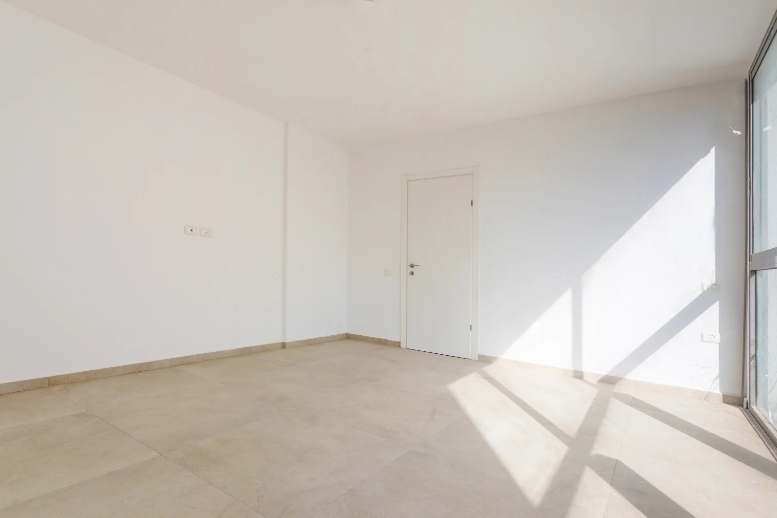 Chambre spacieuse avec sol carrelé et porte blanche