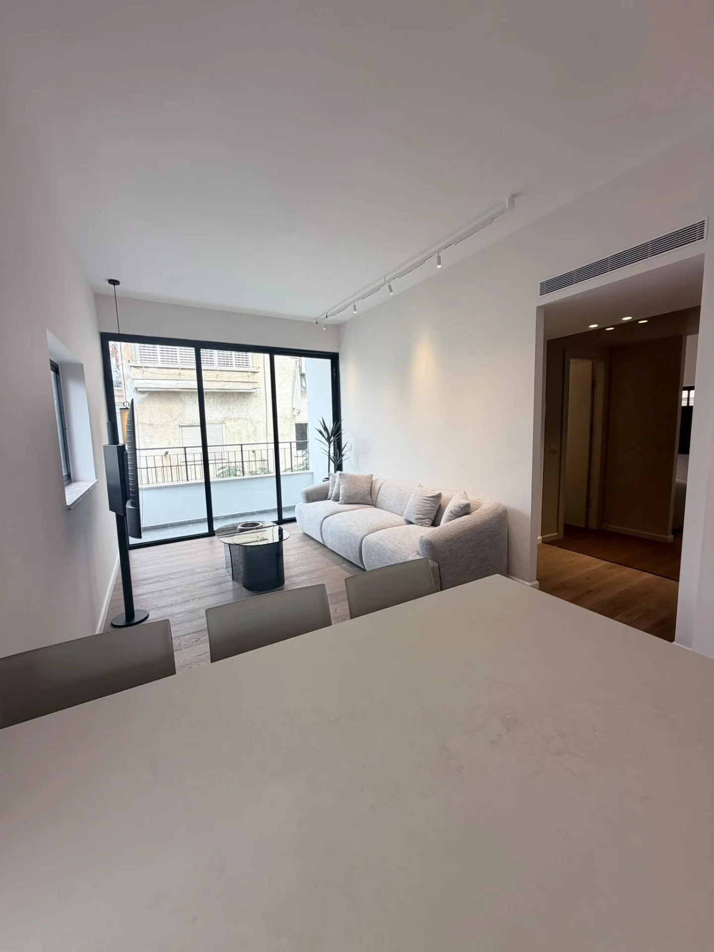 Séjour vu depuis la cuisine, avec canapé et accès au balcon
