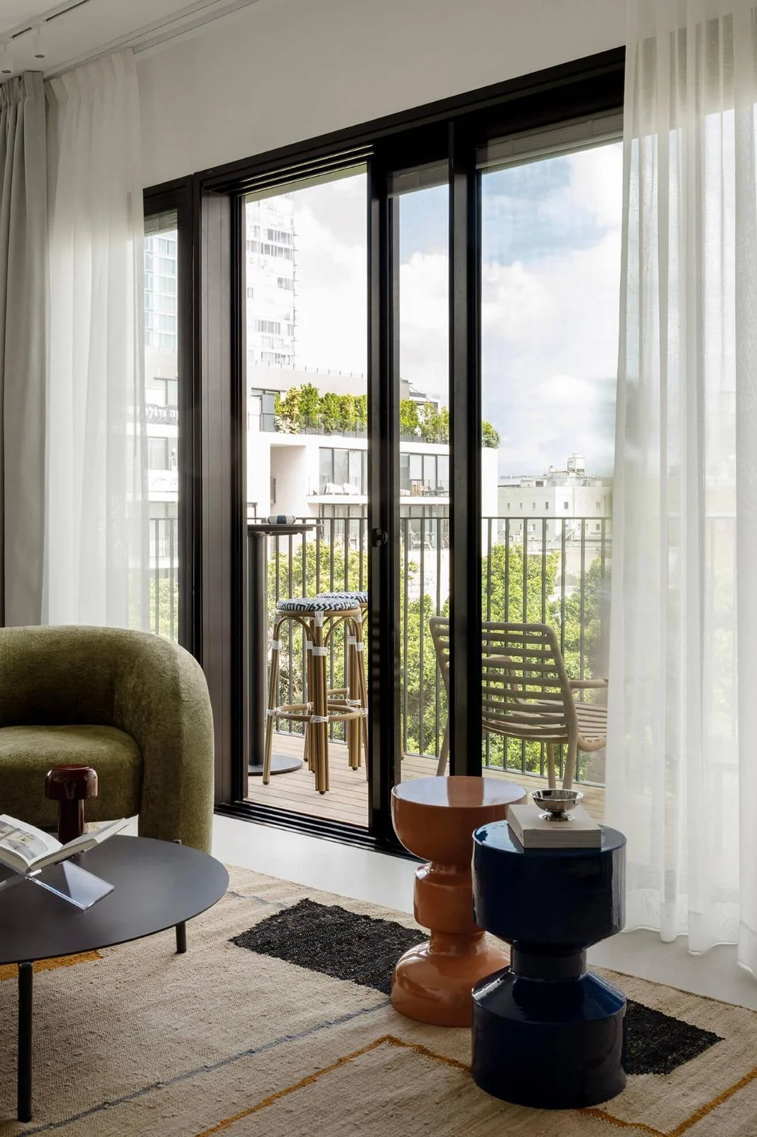 Salon avec fauteuil vert et portes-fenêtres sur balcon