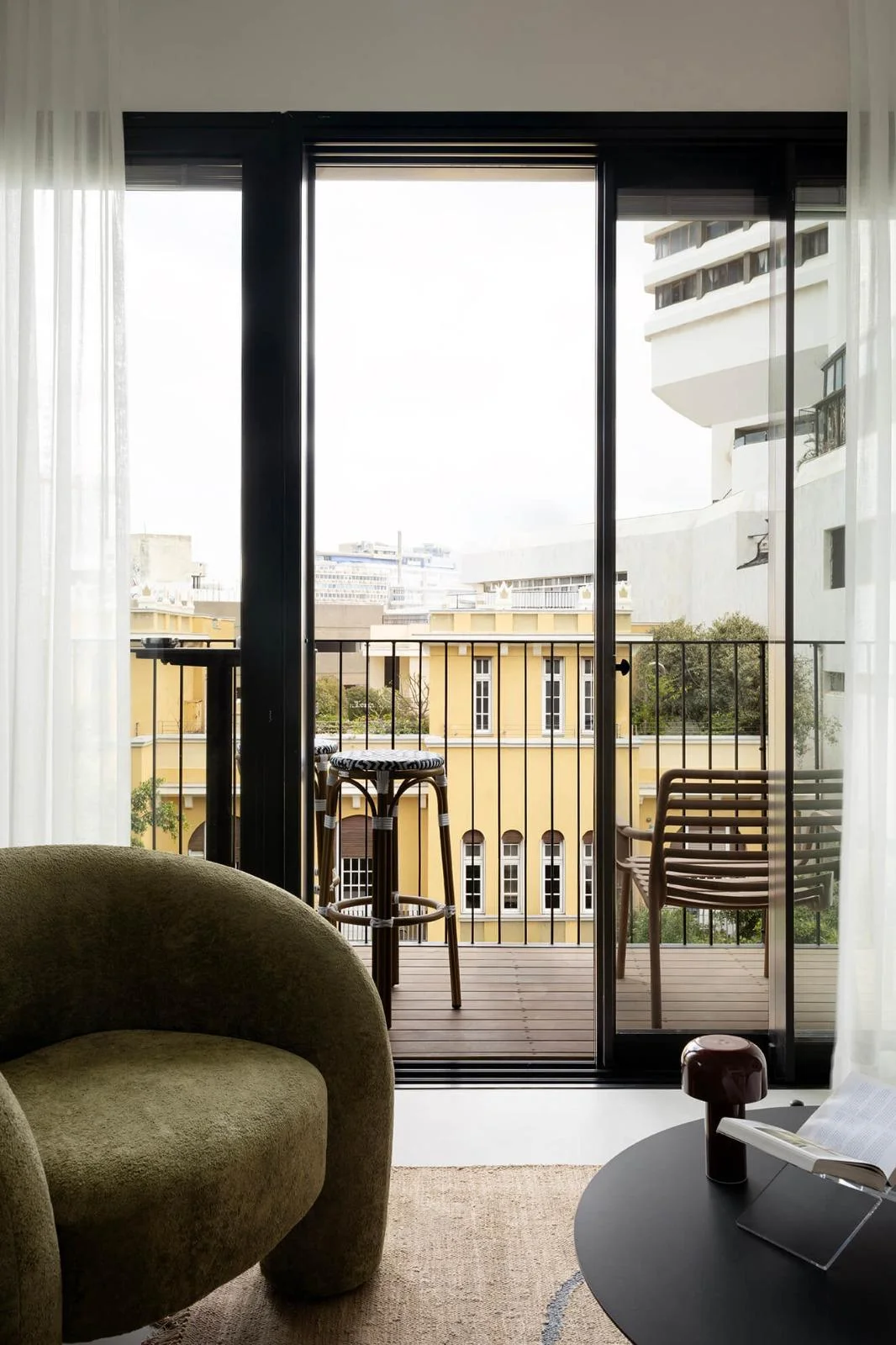 Salon avec fauteuil vert et vue sur balcon