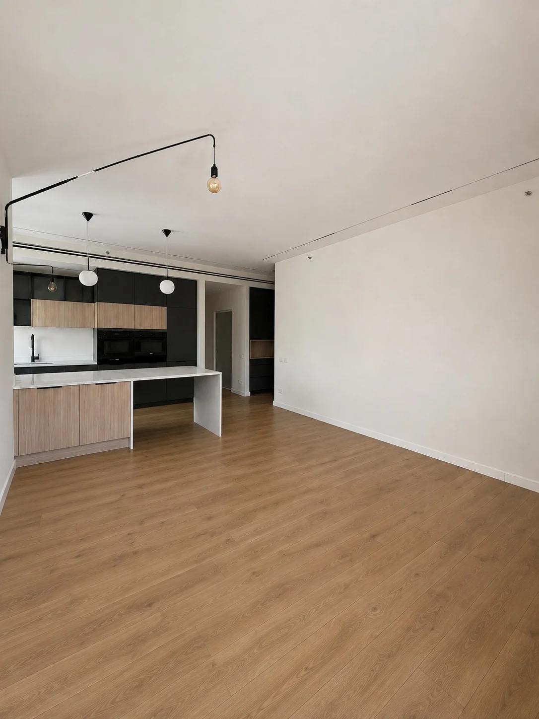 Séjour vide avec parquet bois et cuisine ouverte
