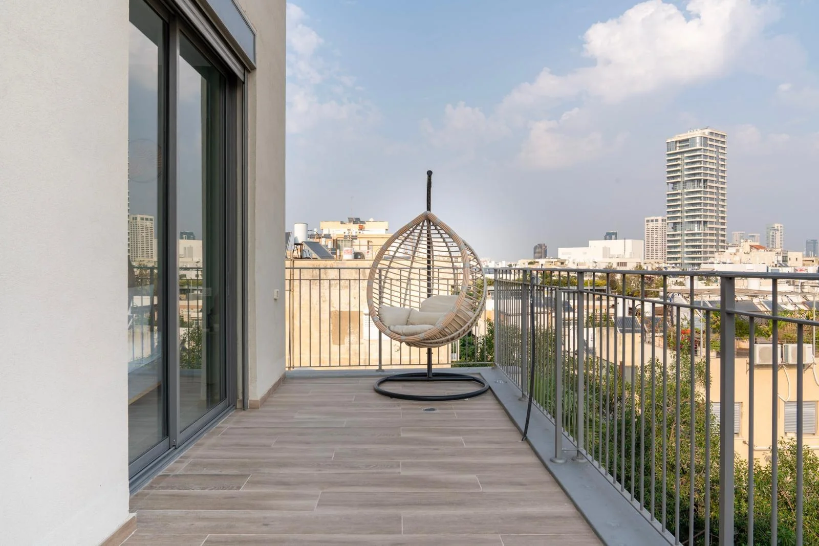 Balcon privatif avec chaise suspendue en rotin et vue sur la ville